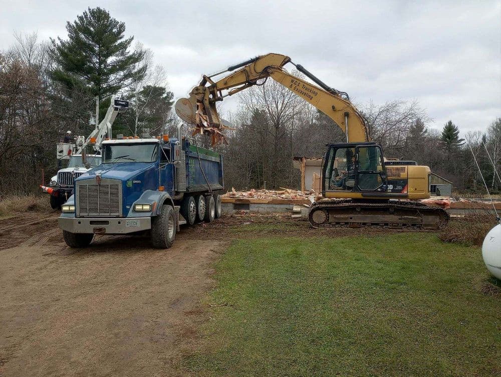 Excavator and dump truck working on a construction site with debris removal.