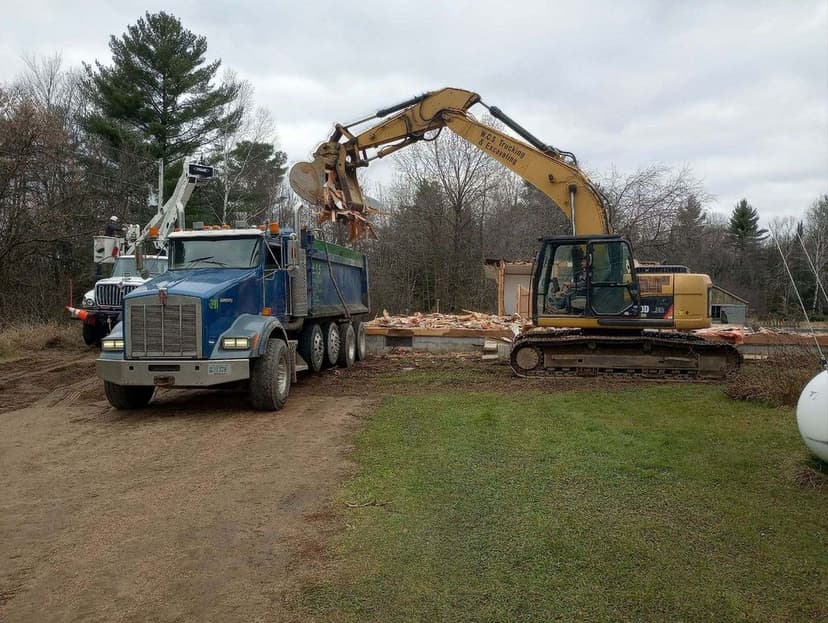 Excavator and dump truck working on a construction site with debris removal.